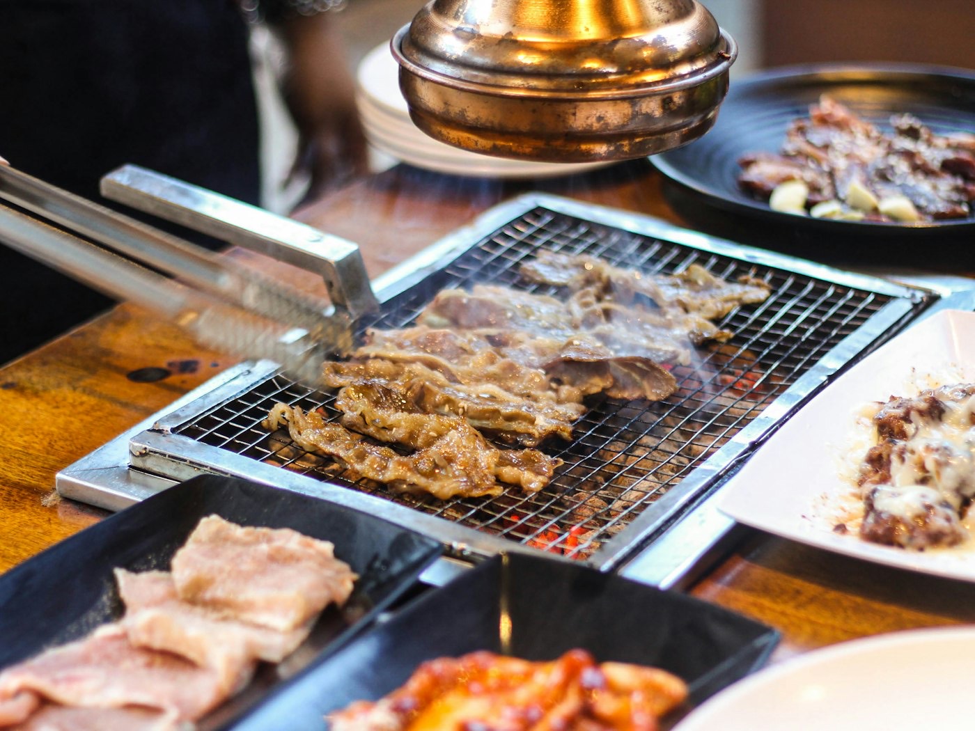 Tongs turning meat on a tabletop grill