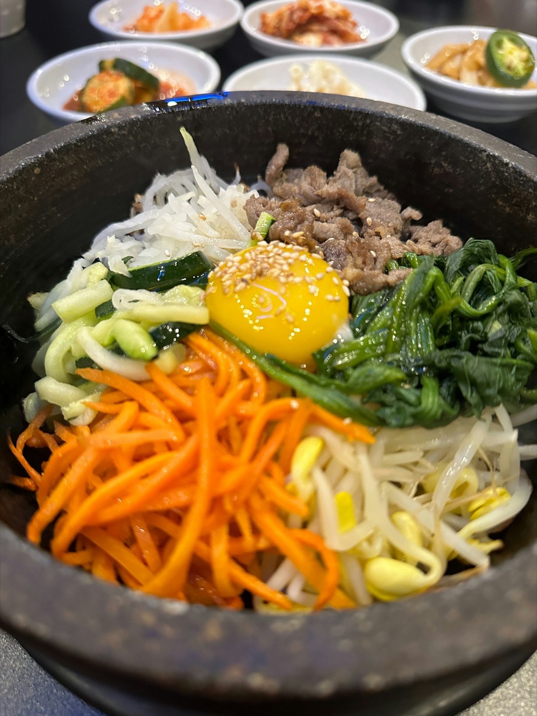 A stone bowl of bibimbap with a raw egg yolk