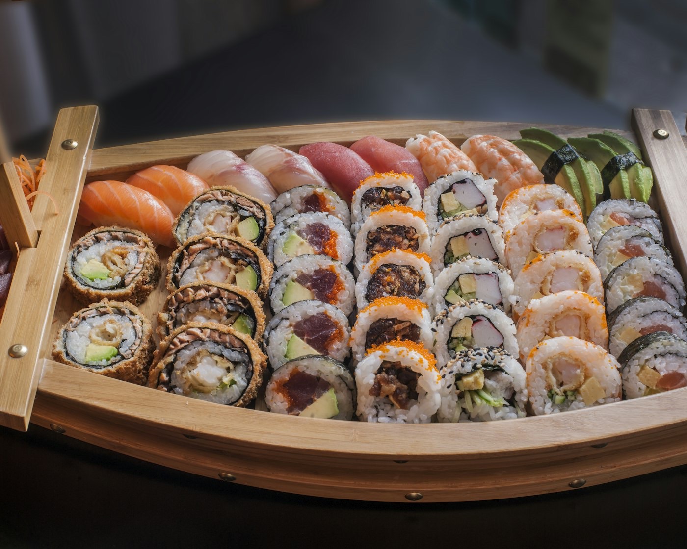 A wooden sushi boat with rolls and nigiri